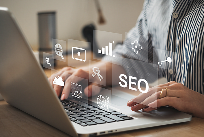 Persona con una computadora manejando gráficas y la palabra SEO saliendo de su pantalla