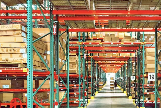 Pasillo de un almacén con estantes de inventario y cajas listas para surtir pedidos